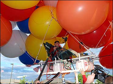 man flies with balloons and lawn chair