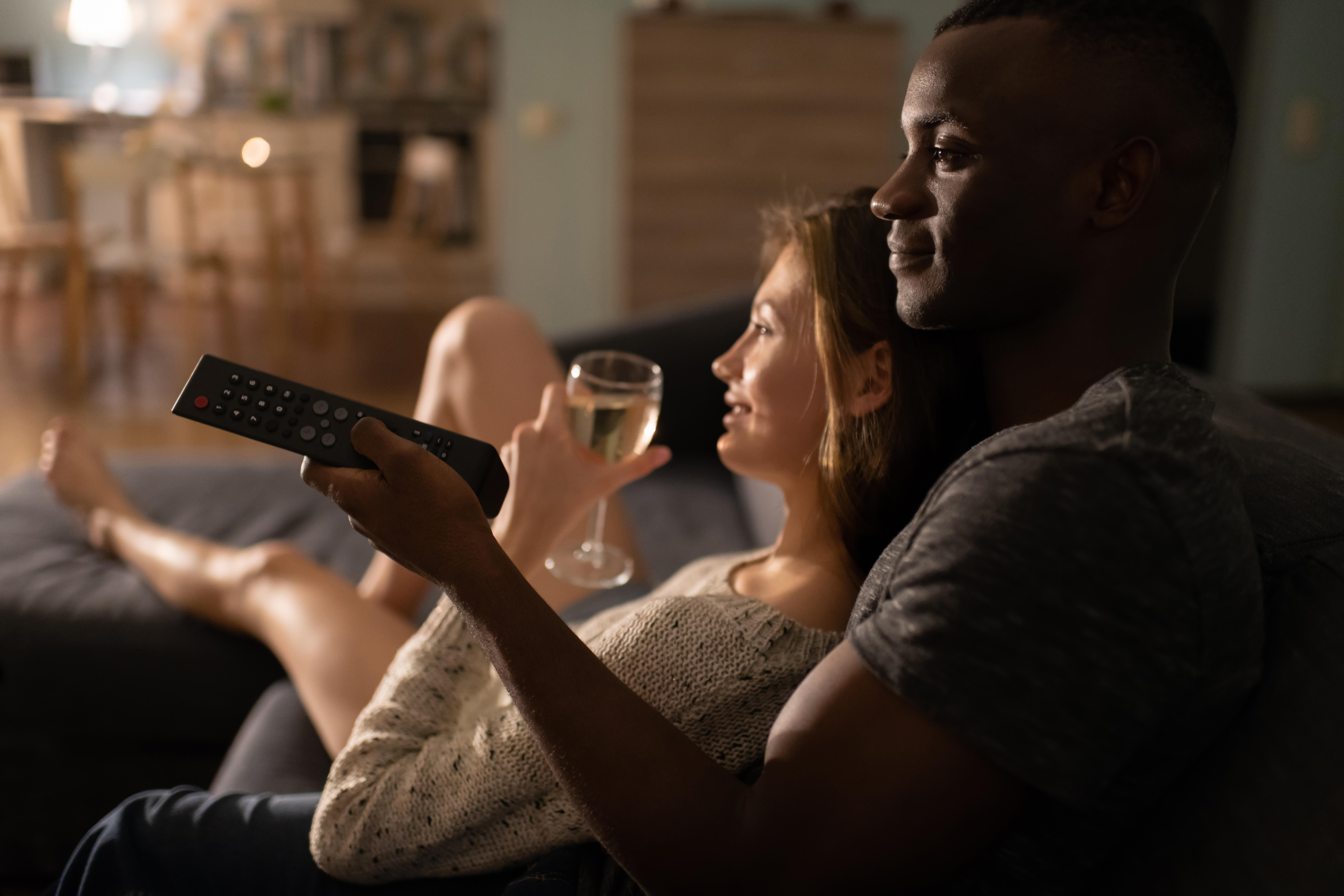 couple watching tv with glasses of wine 