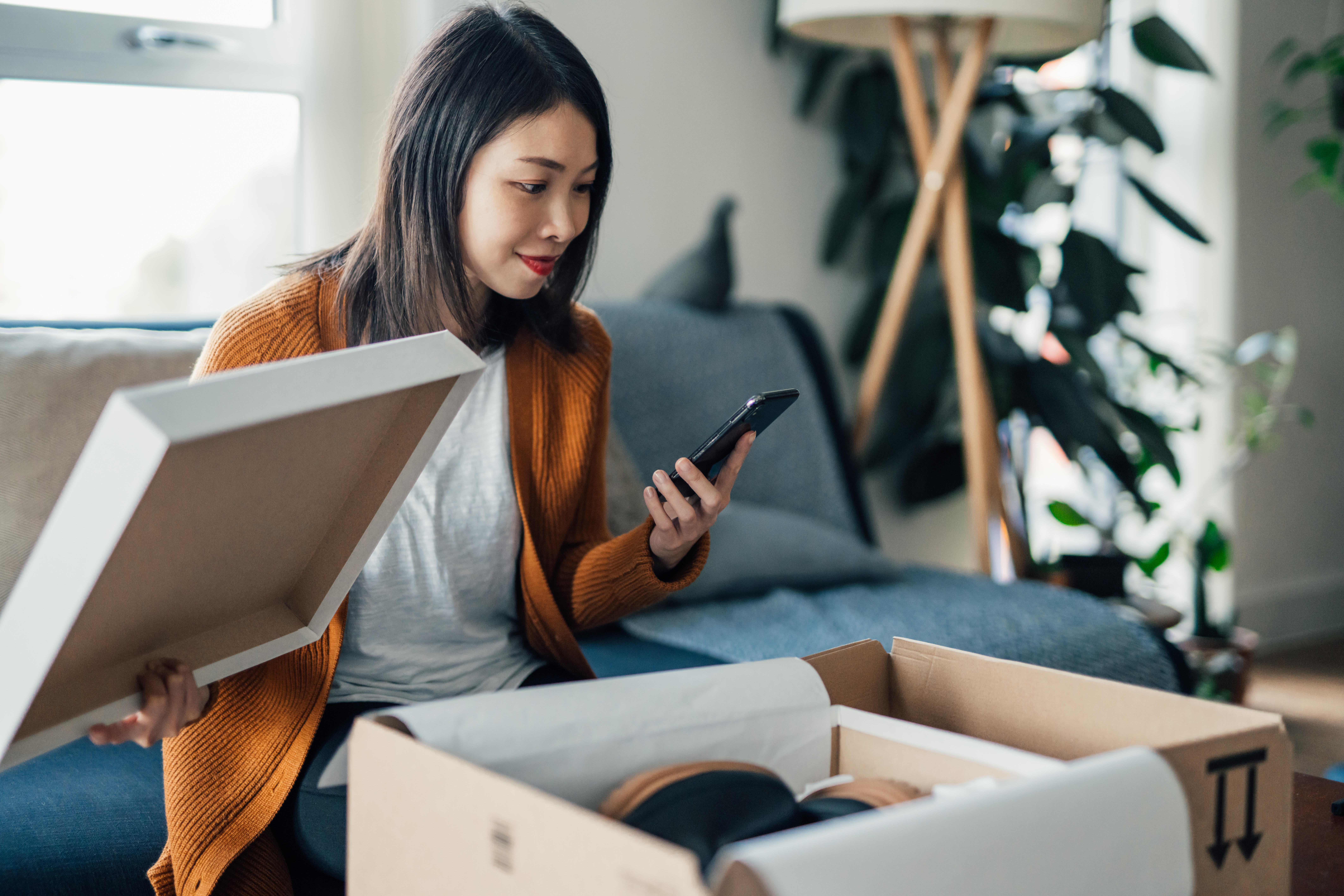 Woman With Smartphone Receiving Parcel Purchased Online 