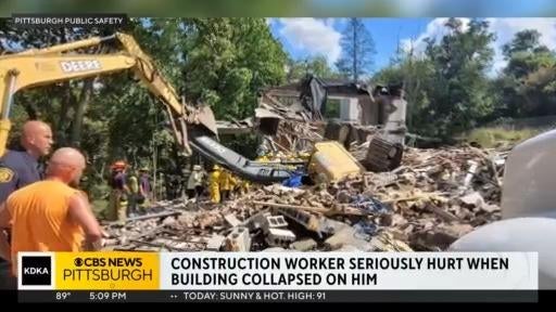 Worker rescued from excavator after building partially collapses during ...
