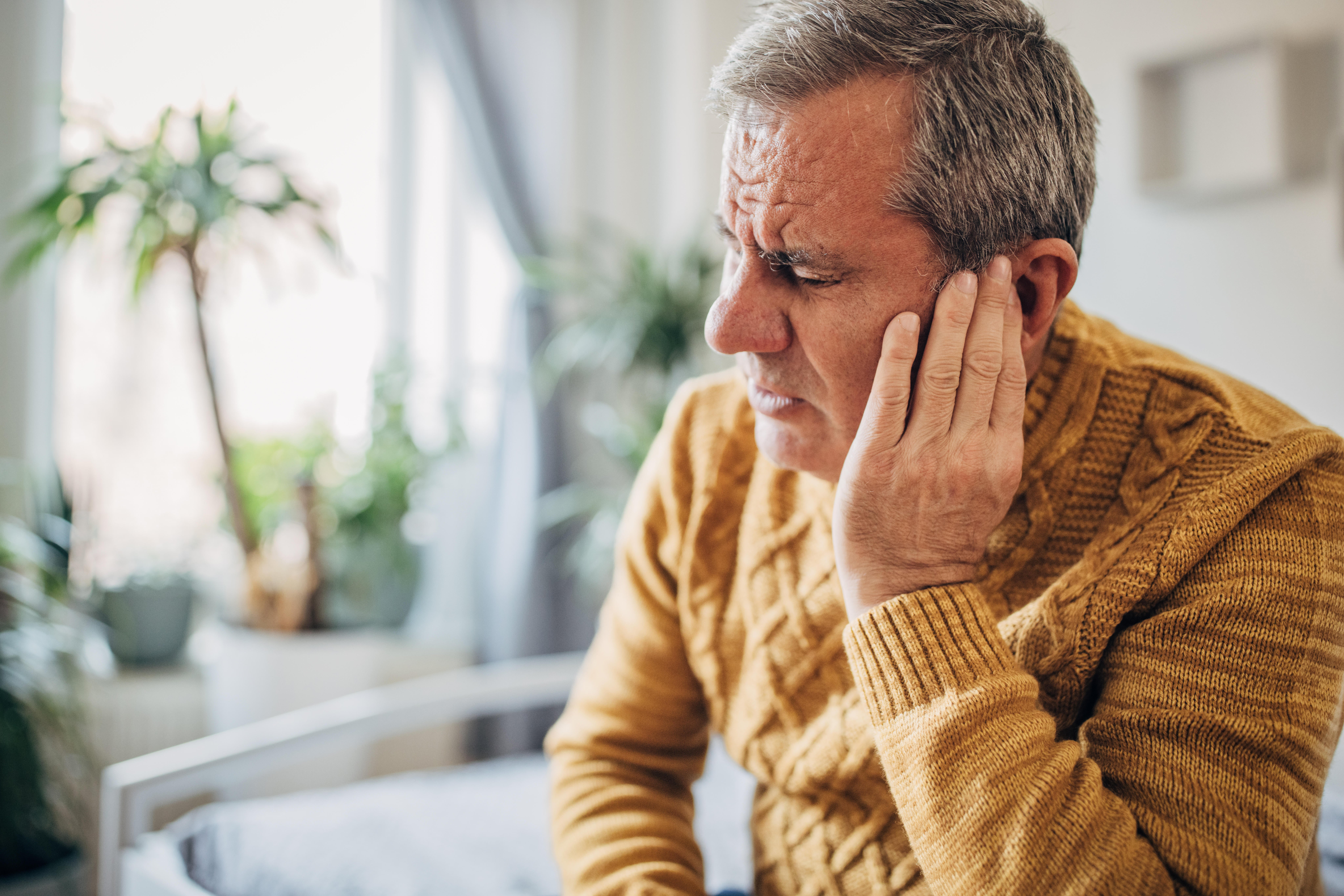 A person holds his hand to his sick ear