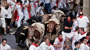 Runners are chased by bulls during the first run of the famous San Fermin festival, in Pamplona 