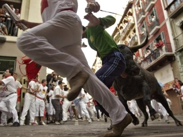Runners are chased by a fighting bull during a bullrun through the streets of Pamplona 
