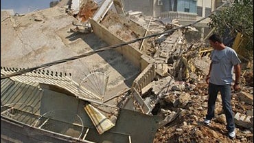 Lebanese man stands next at a destroyed building after it was targeted by Israeli planes 