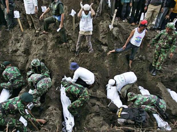 Indonesian soldiers bury the bodies of 24 unidentified bodies of victims of the tsunami 