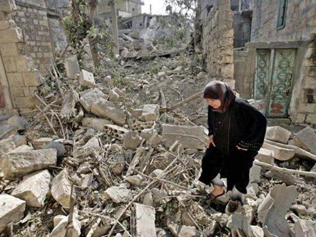 A woman walks in the rubble of destroyed houses after they were targeted by Israeli warplanes missiles 