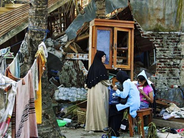 An Indonesian family sits outside of their tsunami ravaged house Friday July 21, 2006 in Pangandaran, Indonesia. 