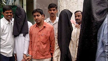 Police officers escort the three suspects, wearing black hoods over their heads, outside the Anti Terrorist Squad office in Bombay 