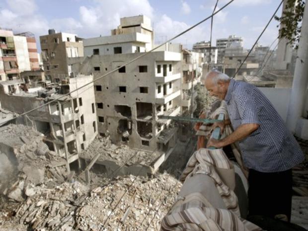 Lebanese Samir Taan Waheb, standing on his apartment balcony, inspects the adjacent destroyed buildings 