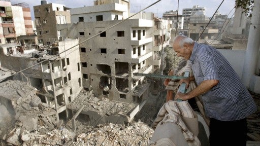 Lebanese Samir Taan Waheb, standing on his apartment balcony, inspects the adjacent destroyed buildings 