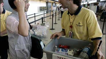 Japanese traveler Toshihiko Sato, who was to board a flight to Tokyo, second from left, carrying hair creme in a plastic bag, is told by an airport worker, who refused to be identified, that it cannot be brought on board the plane, Friday, Aug. 11, 2006 a 