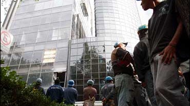 Construction workers watch the building they just evacuated after an earthquake in downtown Mexico City, Mexico, Friday, Aug. 11, 2006. 