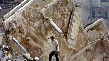 A Lebanese man walks past a destroyed apartment building 