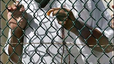 A detainee holds prayer beads by a fence inside the medium security portion of Camp Delta detention center, at the Guantanamo Bay U.S. Naval Base, Cuba, Sept. 19, 2006. 