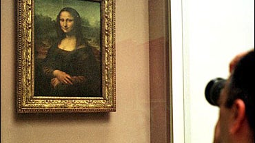 A man takes a photograph of The Mona Lisa painting, behind a protective glass, in the Louvre museum 