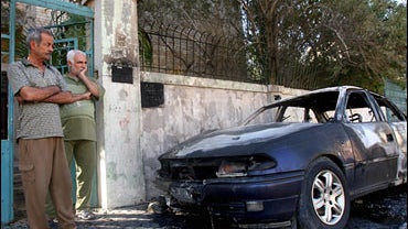The owner, right, views his destroyed car in front of his home in central Baghdad Friday Sept. 29, 2006 after unknown attackers planted explosives. 