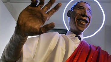 A smiling, life-sized sculpture of Barack Obama with a blue neon halo circling his head 