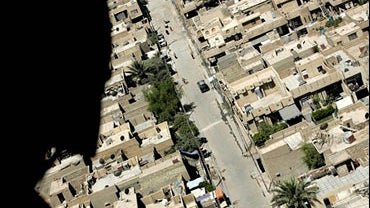 A US helicopter gunner is silhouetted as he looks over deserted streets in central Baghdad 