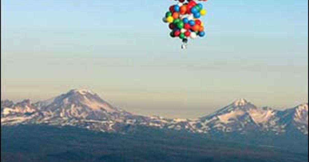 man flies with balloons and lawn chair