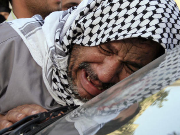 A relative of Saeed Chmagh, an Iraqi driver working with Reuters, weeps as he walks next to the vehicle carrying his coffin outside a Baghdad hospital morgue, 13 July 2007. 