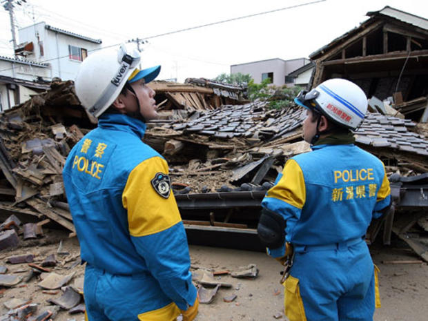 Niigata Police team pass by a house destroyed by the magnitude 6.8 earthquake on July 17, 2007 in Kashiwazaki, Niigata Prefecture, Japan. 