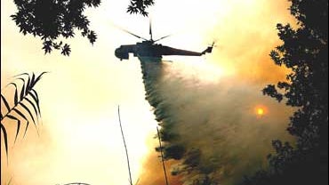 A helicopter drops water in the forest near Ancient Olympia 