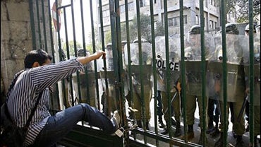 An Iranian student kicks a gate of Tehran University during a protest against President Mahmoud Ahmadinejad, as anti-riot police officers stand behind the gate, in Tehran, Iran, Monday, Oct. 8, 2007. 