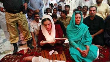 Benazir Bhutto prays next to the grave of her father 