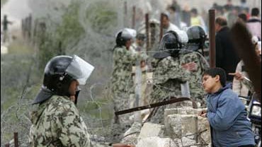Egyptian border guards, left, stand on the border wall between Gaza Strip, right, and Egypt in Rafah 