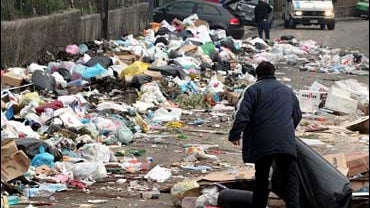 A man handles a bag amid uncollected garbage in the Casoria district on the outskirts of Naples, Italy 