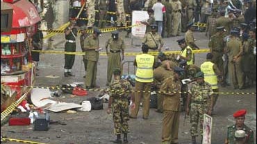 Sri Lankan police investigators search the site of an explosion at the railway station in Colombo 