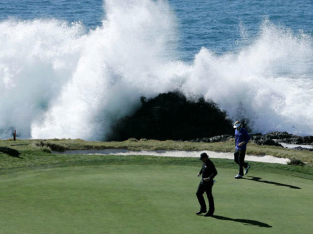Waves crash on the scenic seventh hole as Phil Mickelson and Brandt Snedeker walk the green  