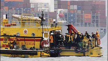 Workers conduct rescue operations where the Ukrainian boat floats upside down in Hong Kong 
