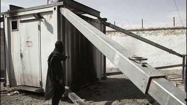 An Afghan worker points to the burned side of a mobile phone company tower 