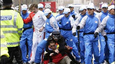 A police officer tackles a demonstrator during the Olympic torch relay in London 