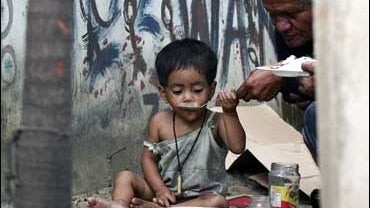A homeless girl gets a little help from her elder relative as she eats her lunch 
