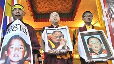 Exiled Tibetans hold portraits of the Dalai Lama and Panchen Lama during a candlelit vigil 
