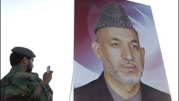 An Afghan soldier photographs a giant portrait of Afghan President Hamid Karzai 