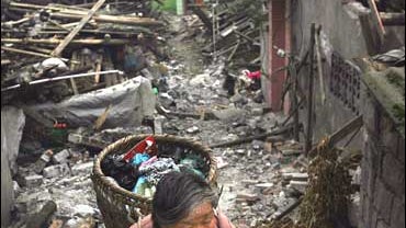 A Chinese earthquake survivor carries her only remaining possessions 