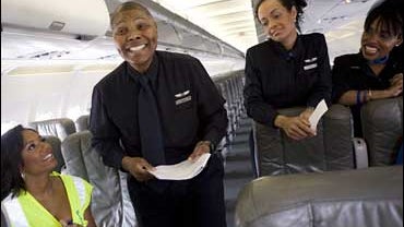 In this image released by TLC, Melanie Brown, host of the new singing competition "The Singing Office," left, listens as Jet Blue flight attendant Kraig auditions for the show aboard one of Jet Blue's Airbus A320 at the airport in Long Beach, Calif., on A 