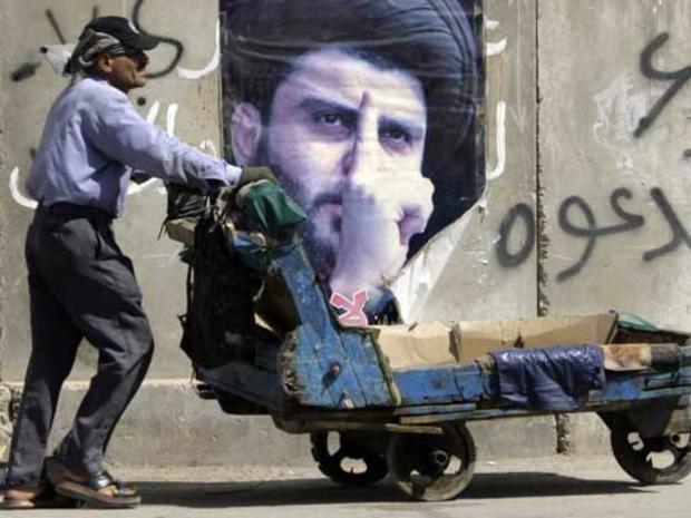 A man pushes a cart past a poster of anti-U.S. cleric Muqtada al-Sadr in Baghdad's Shiite enclave of Sadr City, Iraq, Thursday, July 3, 2008. 