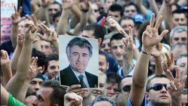 Serbian ultra-nationalists flash 3-fingers salutes and display posters showing Bosnian Serb war crimes suspect Radovan Karadzic, in downtown Belgrade 