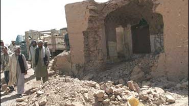 Afghan men look at destroyed house in Azizabad village in the Shindand district of Herat province, Afghanistan 