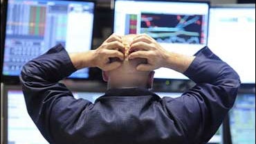 Specialist Justin Bohan holds his head as he works at his post on the floor of the New York Stock Exchange 