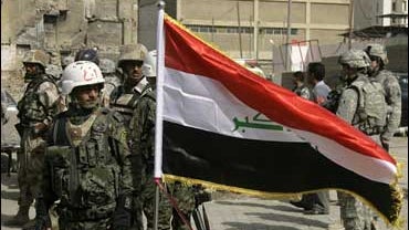 Iraqi and American soldiers stand around an Iraqi flag during a ceremony that marked the reopening of al-Rasheed Street in central Baghdad 