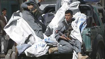 Afghan security men on a vehicle carrying the bodies of foreigners shot outside a DHL office in Kabul 