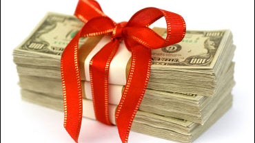 Stack of money wrapped in red bow and ribbon. 