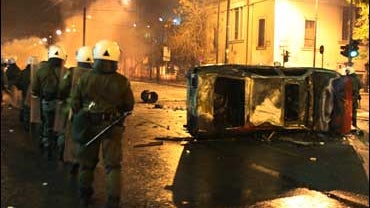 Athens Police Pass By A Burnt-Out Car During Riots Dec. 7, 2008 