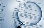 blue toned selective focus shot of resume and magnifying glass 