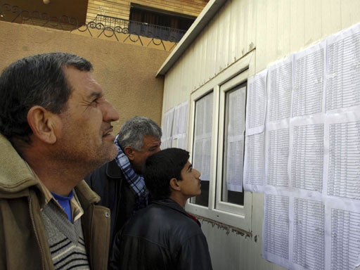 Displaced people look for their names on a voter registration list to find their polling center for the upcoming provincial elections in Sulaimaniyah 